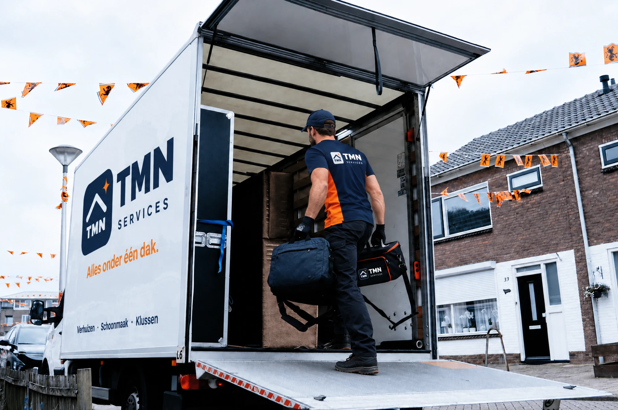 Medewerker van TMN Services laadt tassen in de verhuiswagen met het TMN-logo